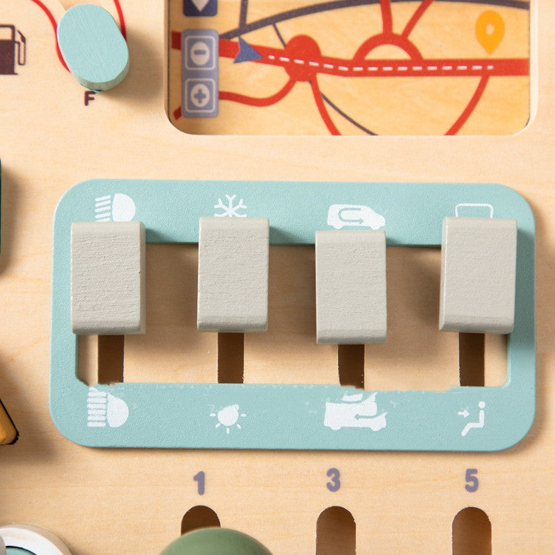 Close-up of the gear-slider panel on the wooden busy board, with four sliding levers above engraved numbers and small icons for lights, wipers and indicators