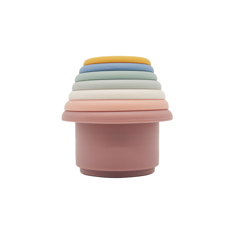 Silicone stacking cups nested into a single tower in a cool palette of dusty pink, grey, blue and cream