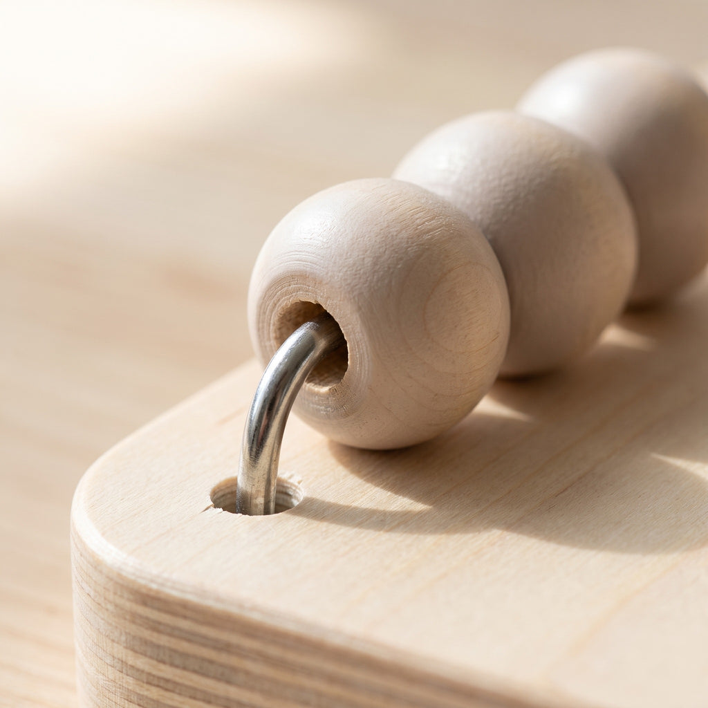 Macro of wooden beads on the curved wire of the counting frame where it meets the birch base