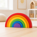 Classic rainbow wooden stacker assembled on a wooden floor in a bright, softly furnished playroom