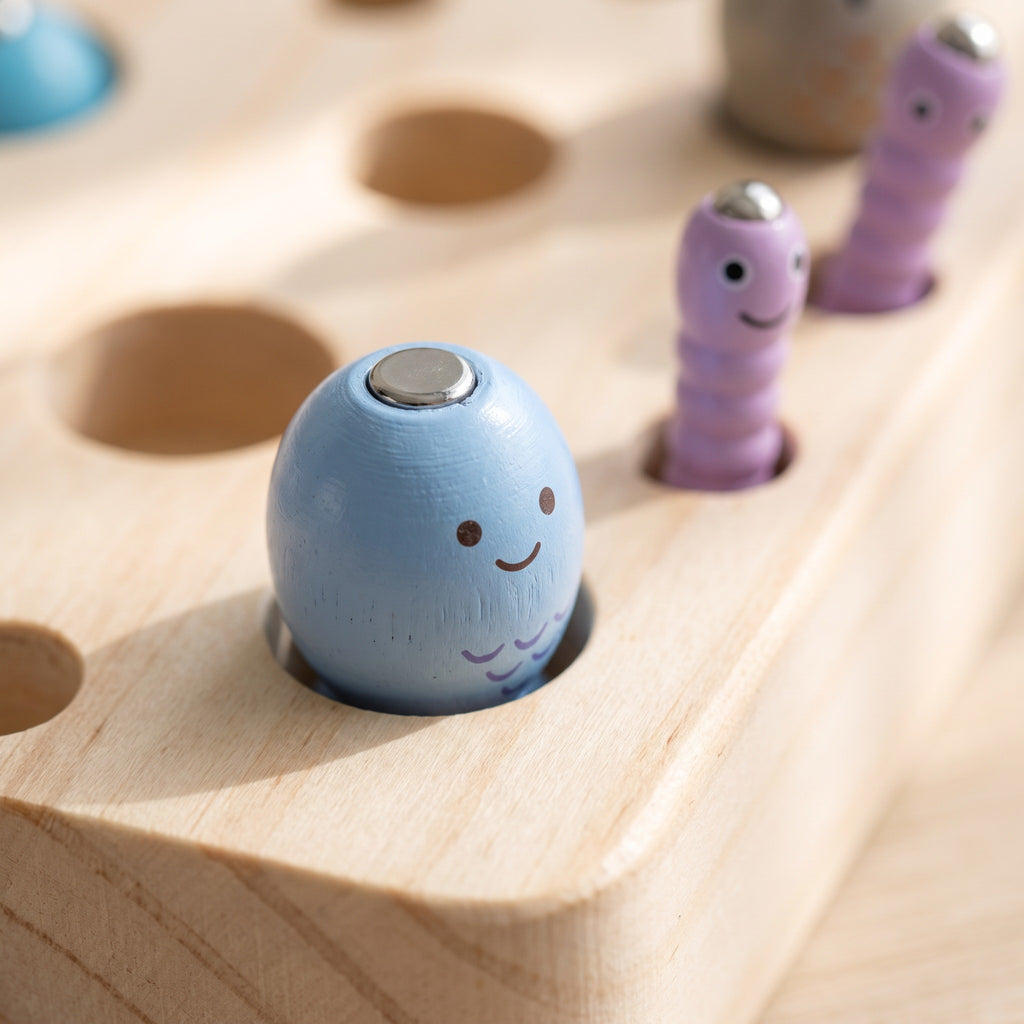 Macro of the pastel wooden fish and bug pieces showing painted faces and magnetic discs