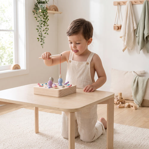 Child lowering the magnetic rod to catch a pastel wooden fish from the birch tray