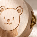 Macro of the engraved bear face on the wooden ring drum with a brass jingle catching the light