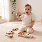 Toddler striking the wooden xylophone with a beater, delighted at the sound