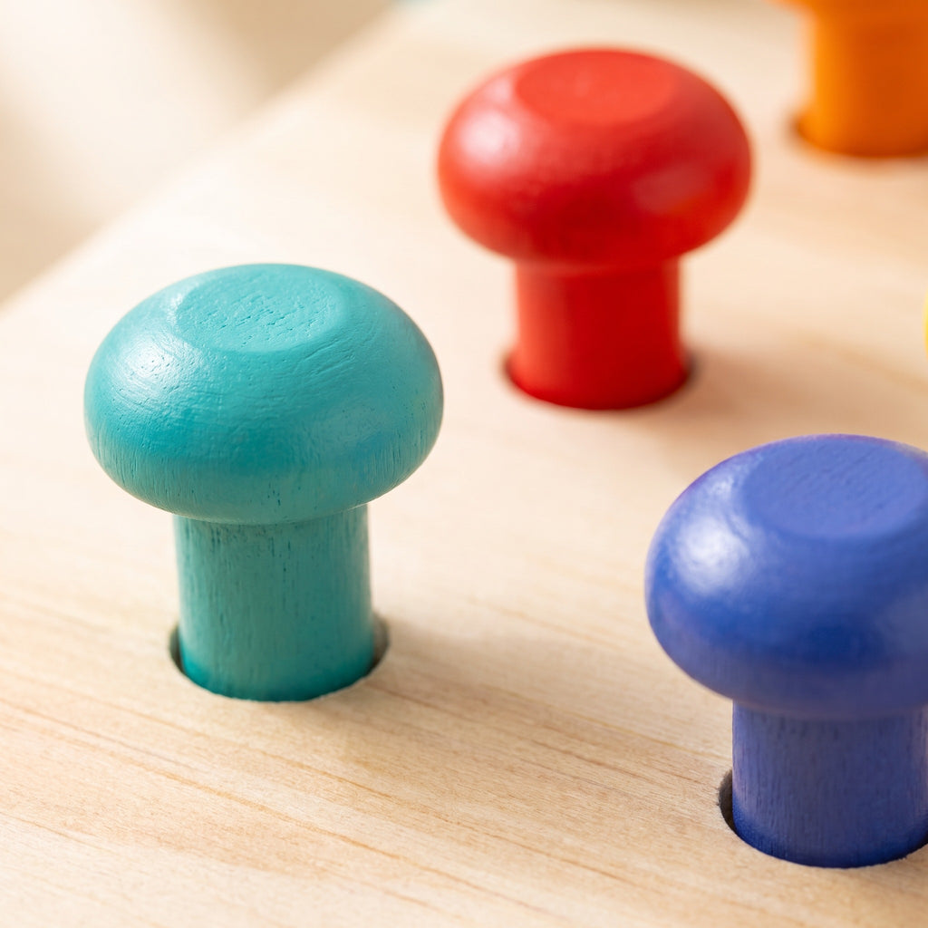 Macro of teal, red and blue mushroom-head pegs standing in their drilled holes