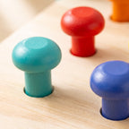 Macro of teal, red and blue mushroom-head pegs standing in their drilled holes