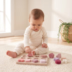 Baby pressing a soft silicone triangle into its well on the shape stacker tray