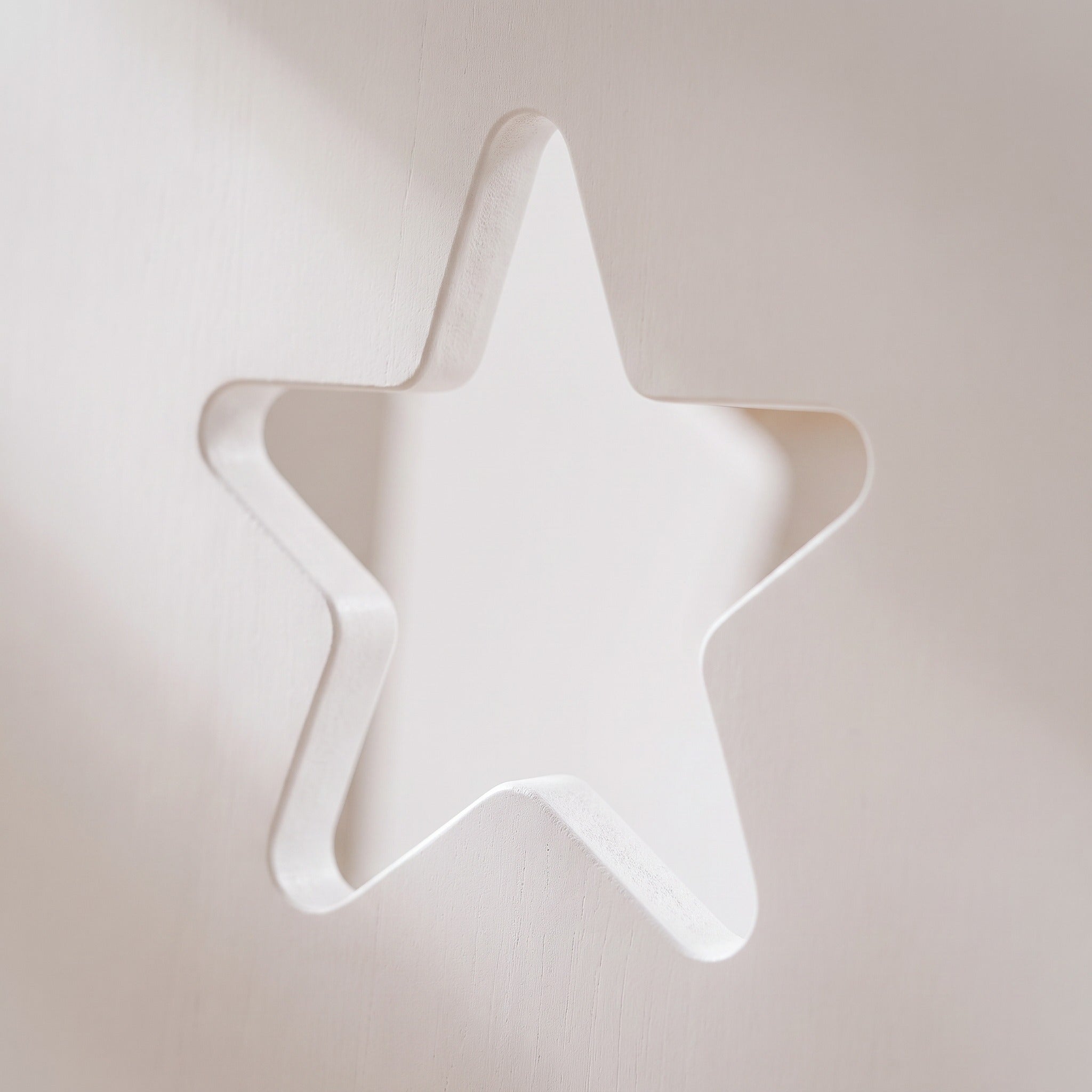 Macro of the star cut-out in the white painted toddler tower panel, showing the rounded child-safe edge
