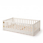 Montessori floor bed with rails and door, twin size white, gate closed on the front left, on a white background