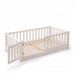 Twin size white Montessori floor bed with the front-left gate swung open, showing brass hinges and natural wood slats