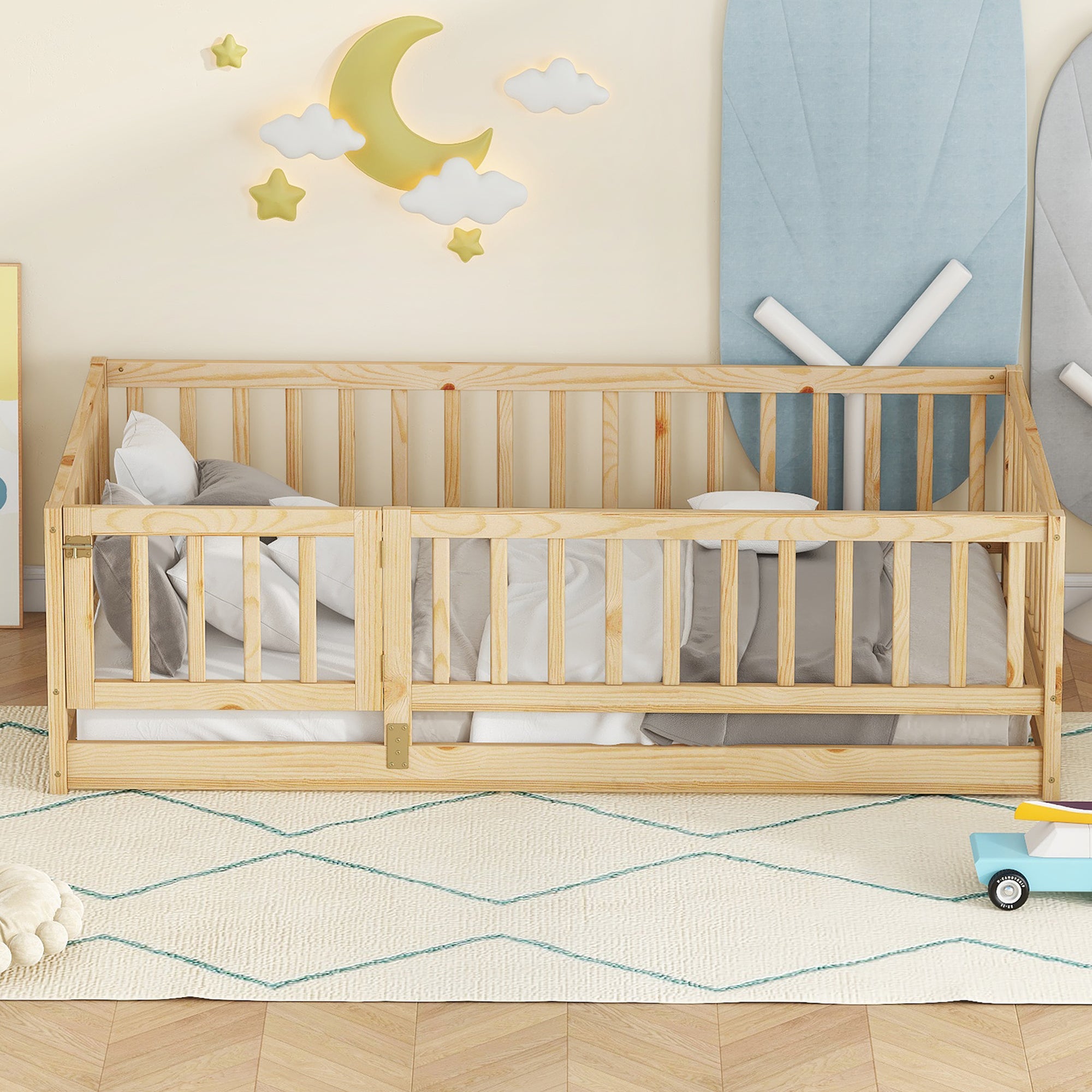 Twin size oak Montessori floor bed made up with white bedding in a nursery with a moon and cloud wall display