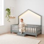 Toddler climbing into the twin size grey Montessori floor bed with the LED roof lighting on