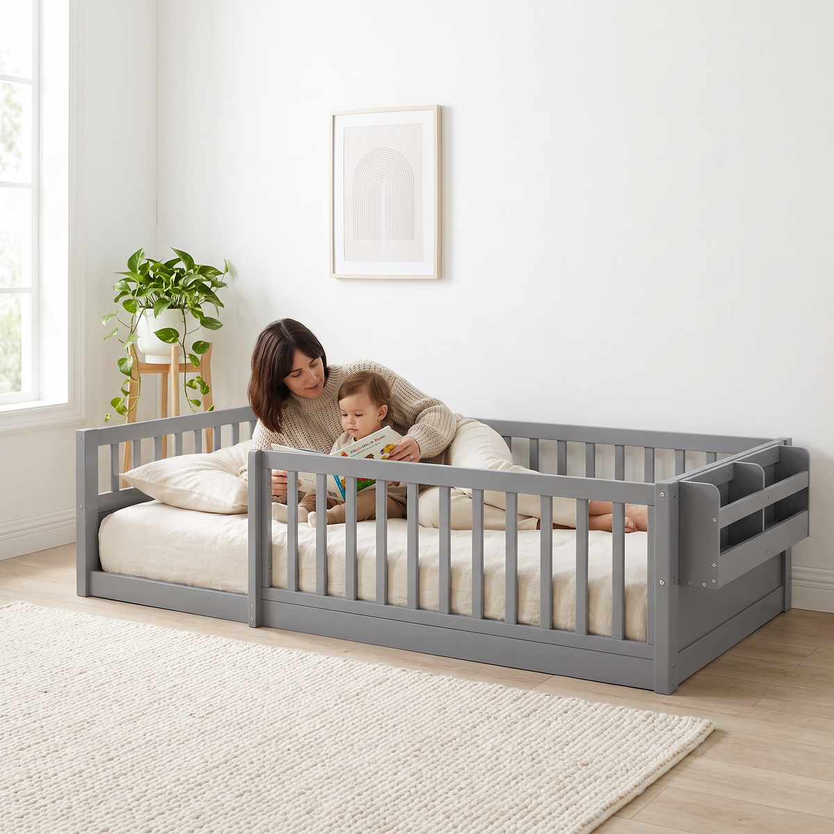 Parent lying inside the twin grey Montessori floor bed reading a picture book to their toddler