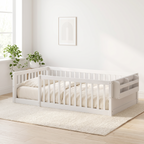 Twin white Montessori floor bed seen from the foot end, showing the full guardrail frame and open doorway