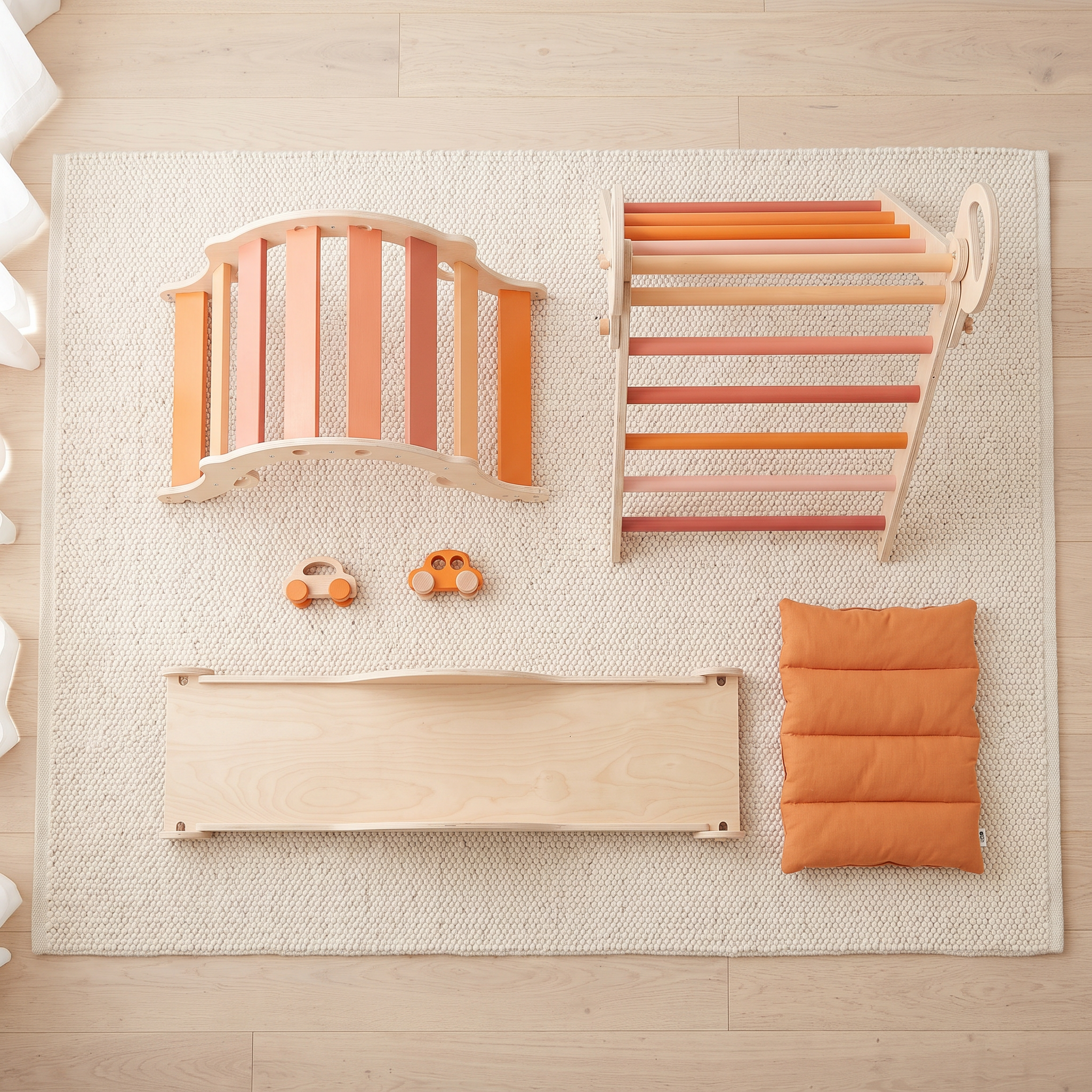 All pieces of the orange Pikler triangle set laid out: triangle, rocking arch, ramp, two wooden cars and cushion